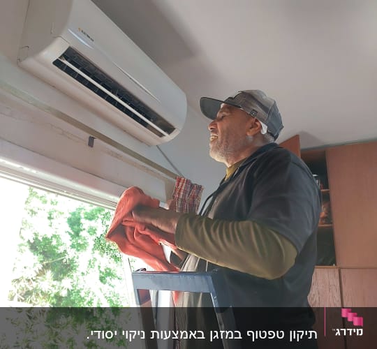 אדם מנקה מזגן עם מטלית אדומה